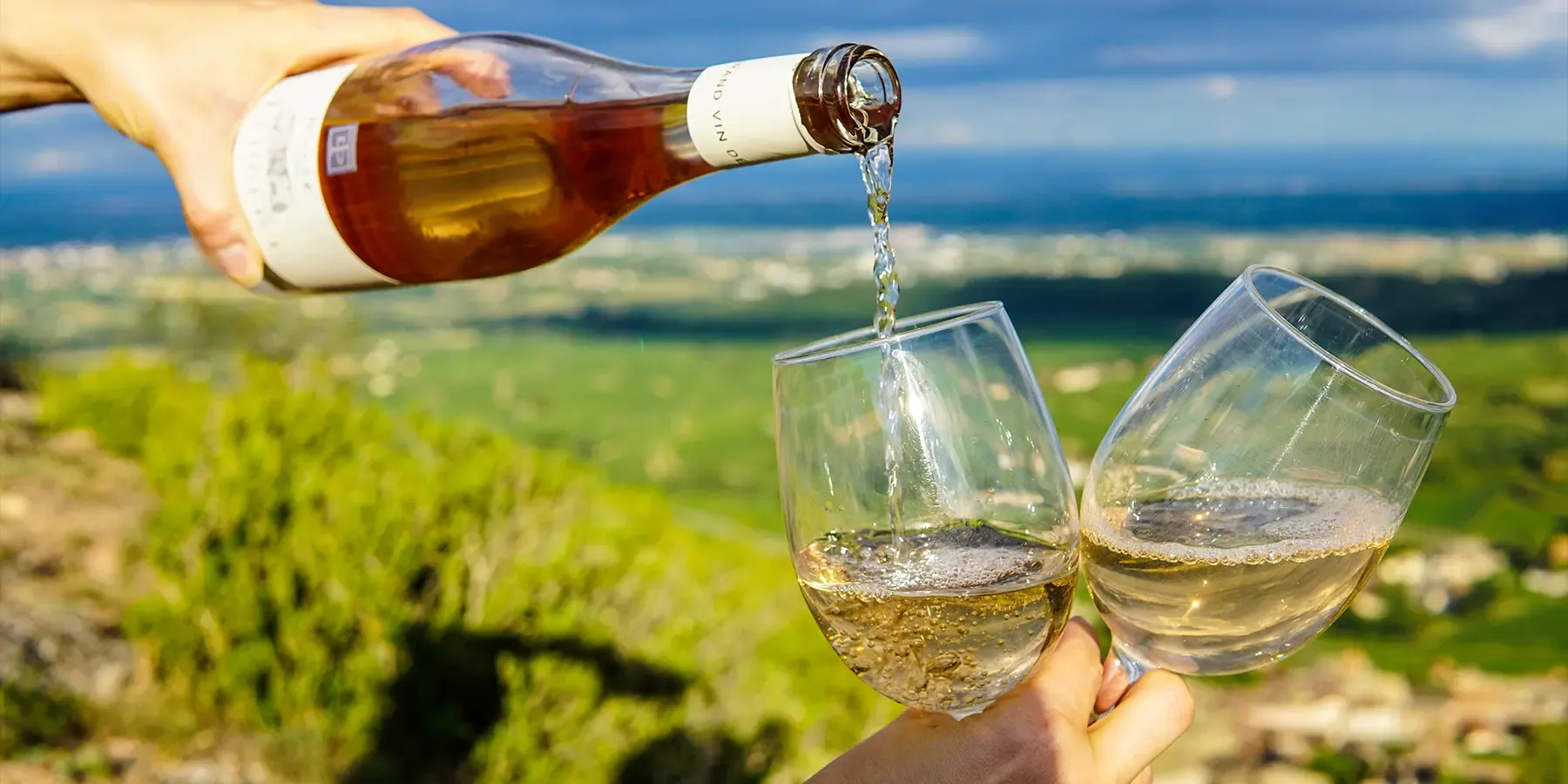 Ros&eacute; wine poured from a bottle into a glass